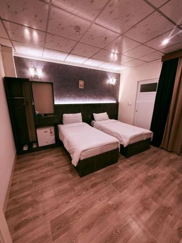 a room with two beds and a flat screen tv at Vote Hotel 1 in Erbil
