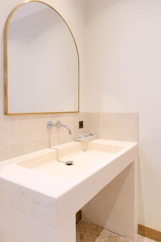 une salle de bain avec un lavabo blanc et un miroir dans l'établissement Maison de charme au cœur des vignes, à Orange