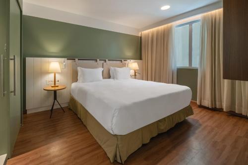 a bedroom with a large white bed and a window at Grand Mercure Rio de Janeiro Copacabana in Rio de Janeiro