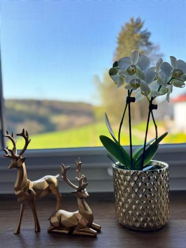 three wooden figurines next to a vase with a plant at harmony holiday, Pension in Kerschenbach