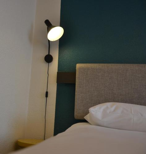 a bedroom with a bed with a lamp next to it at ibis Chambery in Chambéry