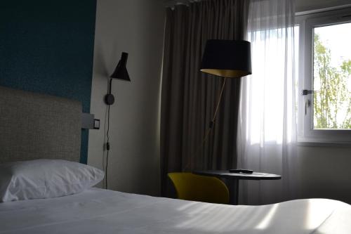 a hotel room with a bed and a window at ibis Chambery in Chambéry