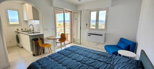 une chambre avec un lit bleu et une cuisine avec des fenêtres dans l'établissement Lovely studio with balcony - near the beach, à Fréjus