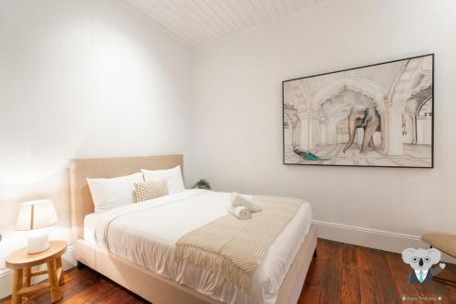 a bedroom with a bed and a painting on the wall at KozyGuru | Balmain | Charming 3 Room cottage in Sydney