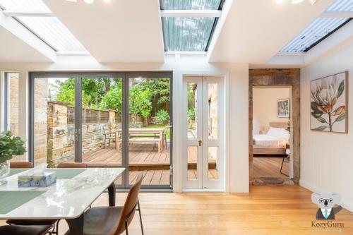 a conservatory with a dining room with sliding glass doors at KozyGuru | Balmain | Charming 3 Room cottage in Sydney