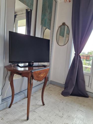 - une télévision sur une table en bois dans une chambre avec fenêtre dans l'établissement Cosy F1 Parking privé, à Saint-Maur-des-Fossés