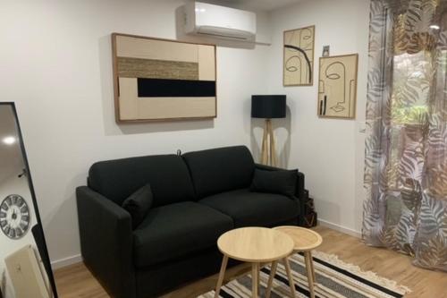 un salon avec un canapé noir et une table dans l'établissement Charming studio for two in Mandelieu-la-Napoule, à Mandelieu-la-Napoule