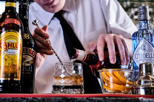 a man in a tie pouring a drink into a glass at Hotel Restaurant Crystal in Erstein