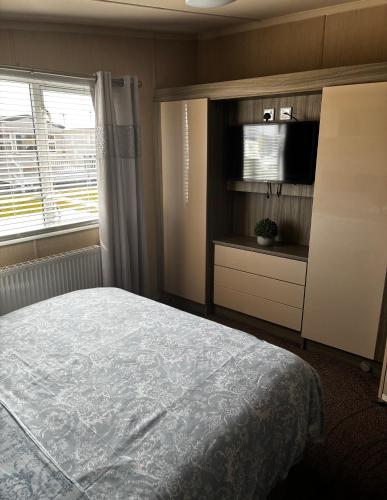 a bedroom with a bed and a tv and a window at caravan to let in Ingoldmells