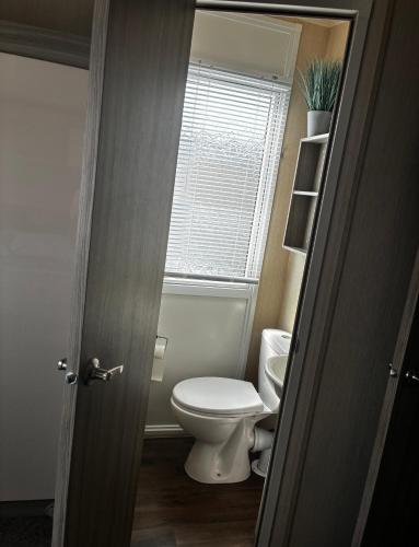 a bathroom with a toilet and a window at caravan to let in Ingoldmells
