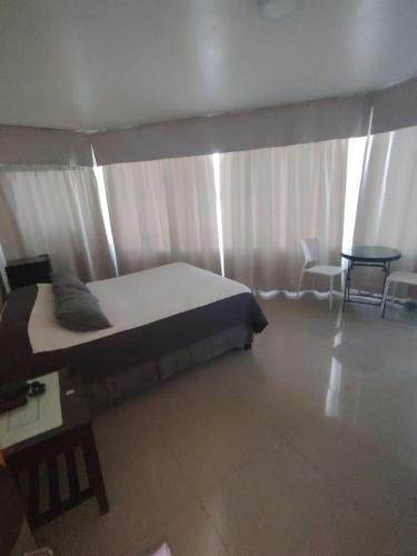 a bedroom with a bed and a table and a window at Hotel Cano in Iquique