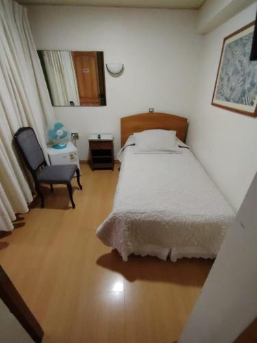 a bedroom with a bed and a chair and a table at Hotel Cano in Iquique