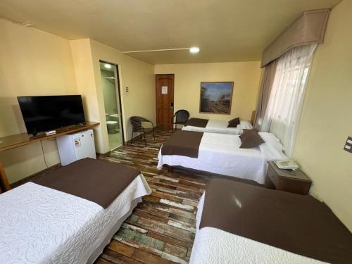 a hotel room with two beds and a flat screen tv at Hotel Cano in Iquique