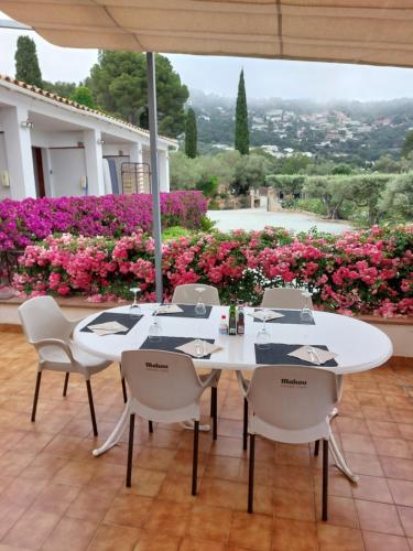 a white table and chairs with pink flowers at Hotel Nuevo Ondina in Begur