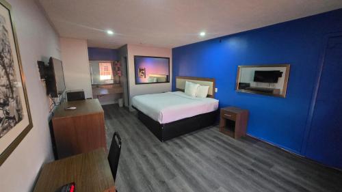 a hotel room with a bed and a blue wall at Jeffersonian Motor Inn by Townhouse, Prentiss MS in Prentiss