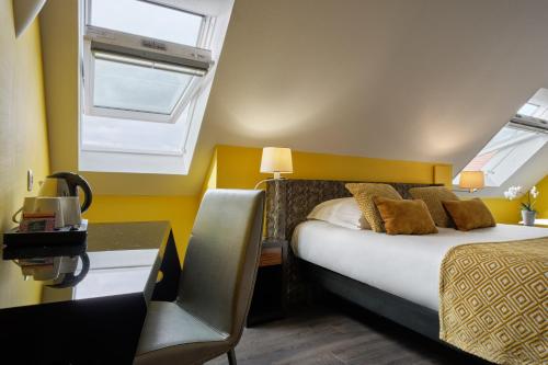 a bedroom with a bed and a desk and a window at Hotel Restaurant Crystal in Erstein
