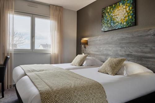 a hotel room with two beds and a large window at Hotel Restaurant Crystal in Erstein