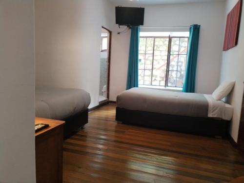 a room with two beds and a window at El Jardín de Jeni in Cusco