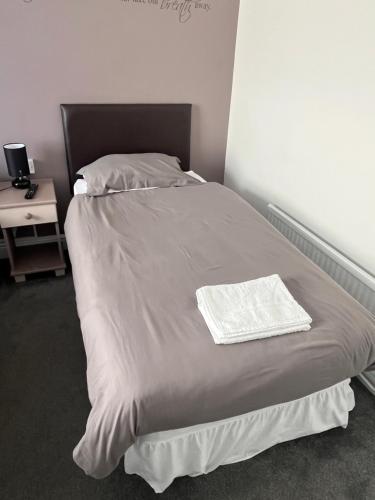 a bed with a white blanket and a night stand at Hampton Hotel & restaurant in Llandrindod Wells