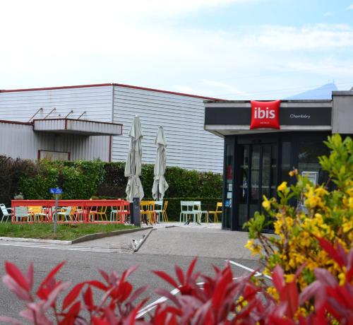 a restaurant with tables and umbrellas in front of a building at ibis Chambery in Chambéry