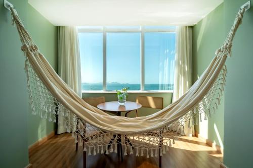 a hammock in a room with a table and a window at Grand Mercure Rio de Janeiro Copacabana in Rio de Janeiro