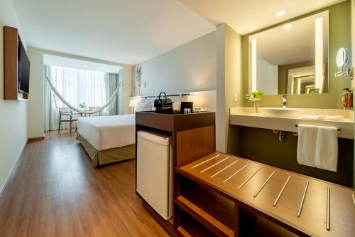 a hotel room with a bathroom with a sink and a bed at Grand Mercure Rio de Janeiro Copacabana in Rio de Janeiro