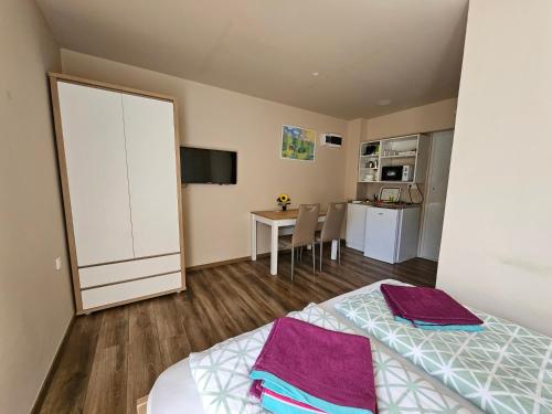 a bedroom with a bed and a kitchen with a table at Babérkák Vendégház in Balatonfüred