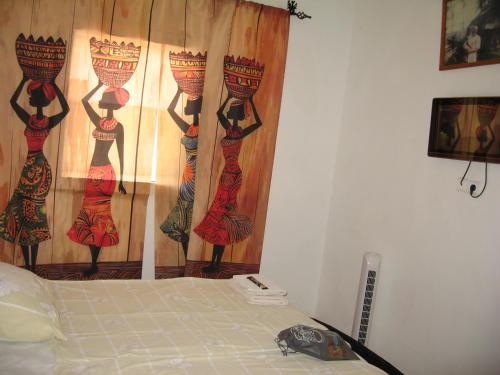 a bedroom with a bed and a curtain with a window with a dress at KEUR MARIE FAYE in Mbour