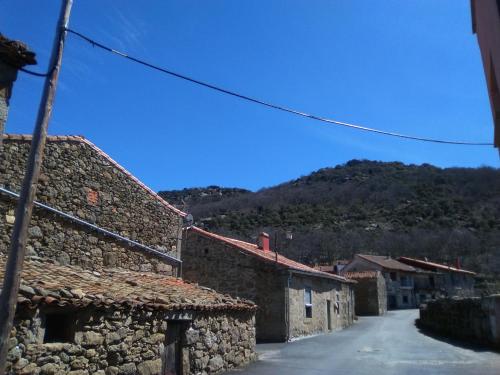 an alley with stone buildings and a mountain in the background at Apartamentos La Covatilla in Neila de San Miguel