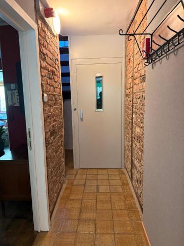 a hallway with a brick wall and a white door at Aux 3 Canards in Stoumont