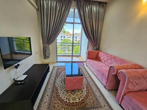sala de estar con sofá rosa y TV en Rosy Retreat, en Tambun