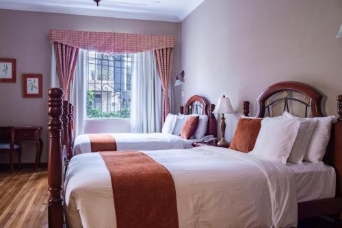 a bedroom with two beds and a window at Casa Aliso Hotel Boutique in Quito