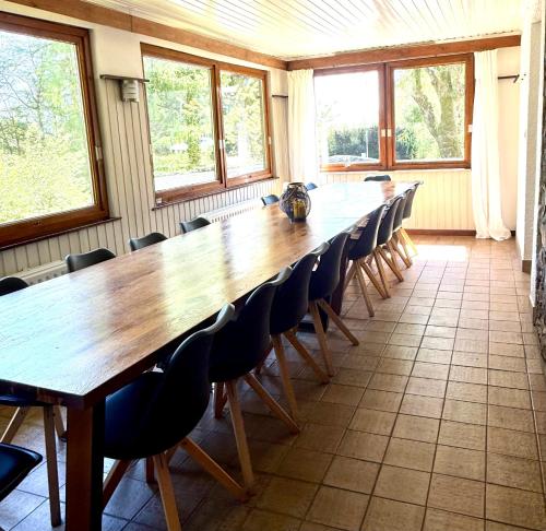a large wooden table and chairs in a room with windows at Aux 3 Canards in Stoumont
