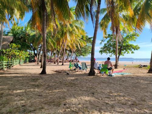 people sitting on the beach under palm trees at Hotel Huacas in Huacas