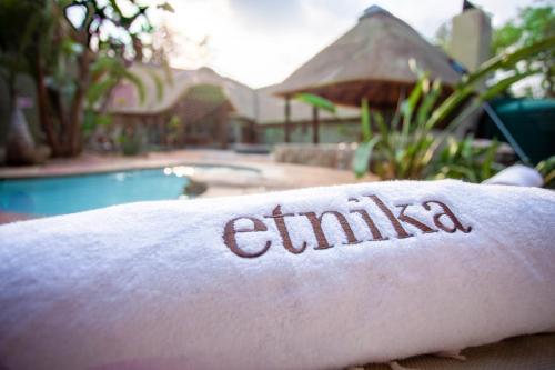 a towel with the word emiya on it next to a swimming pool at Etnika Manor House in Hoedspruit