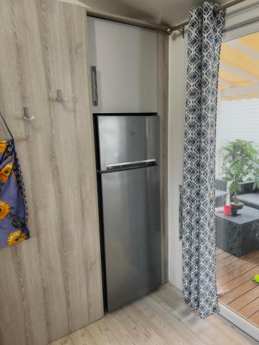 a stainless steel refrigerator in a kitchen next to a window at Mobilhome 8 personnes Camping 4 étoiles Vias plage - la Carabasse in Vias