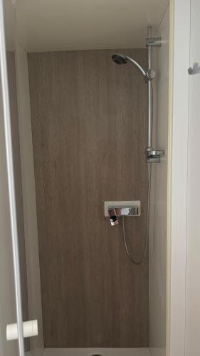 a shower in a bathroom with a wooden door at Mobilhome 8 personnes Camping 4 étoiles Vias plage - la Carabasse in Vias