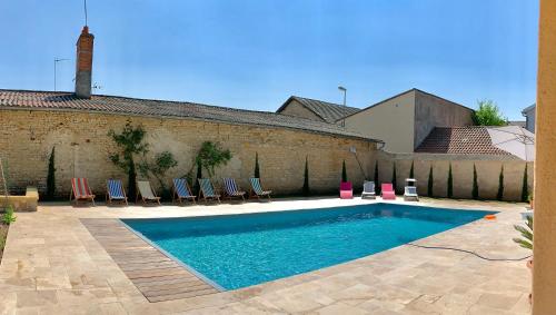 une piscine avec des chaises et un bâtiment dans l'établissement Les Gîtes de La Chartreuse - Jaunay Marigny - 3mnFuturoscope, à Jaunay-Clan