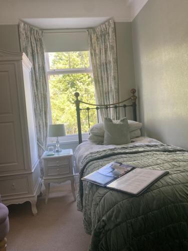 a bedroom with a bed with a window and a table at Kenilworth Guest House in Windermere