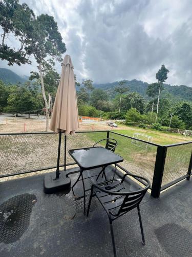 a table and two chairs and an umbrella on a patio at Capital O 91152 Jerot Dusun Campsite in Kampong Bukit Tumboh