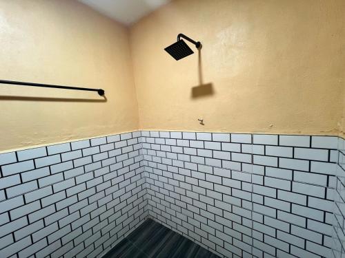 a white tiled shower with a light on the wall at Capital O 91152 Jerot Dusun Campsite in Kampong Bukit Tumboh