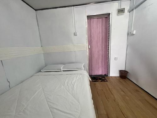 a small room with a bed and a pink door at Capital O 91152 Jerot Dusun Campsite in Kampong Bukit Tumboh