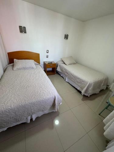 a bedroom with two beds and a night stand at Hotel Cano in Iquique