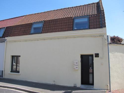 a white building with a door and a brown roof at Loveroom, Les années 80 chez nounours in Templemars