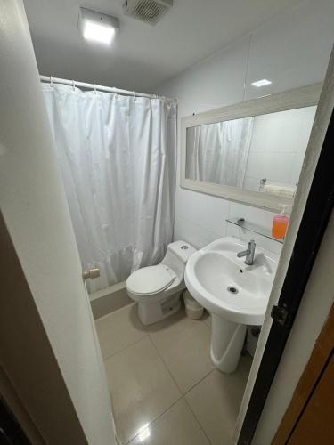 a bathroom with a toilet and a sink and a mirror at Hotel Cano in Iquique