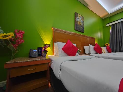 two beds in a room with green walls at Le Paradise Palace Hotel Deira Dubai Al Rigga in Dubai