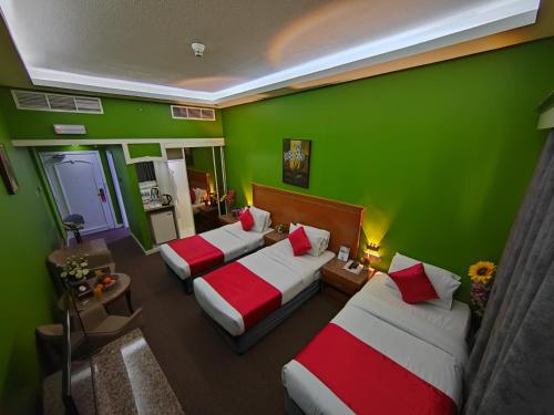 a room with three beds and a green wall at Le Paradise Palace Hotel Deira Dubai Al Rigga in Dubai