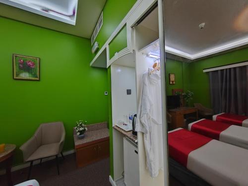 a room with green walls and a bed and a robe at Le Paradise Palace Hotel Deira Dubai Al Rigga in Dubai