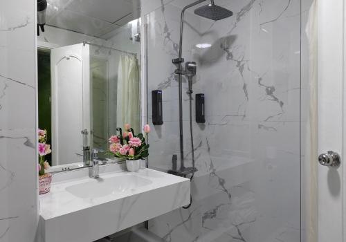 a white bathroom with a sink and a mirror at Le Paradise Palace Hotel Deira Dubai Al Rigga in Dubai