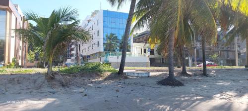 a group of palm trees on a beach with a building at Flat Easy Sunset in João Pessoa